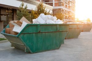 	
Large green dumpsters filled with cardboard boxes and white plastic bags are positioned outdoors near modern apartment buildings at sunset, illustrating the convenience of dumpster rental in Sunnyvale.